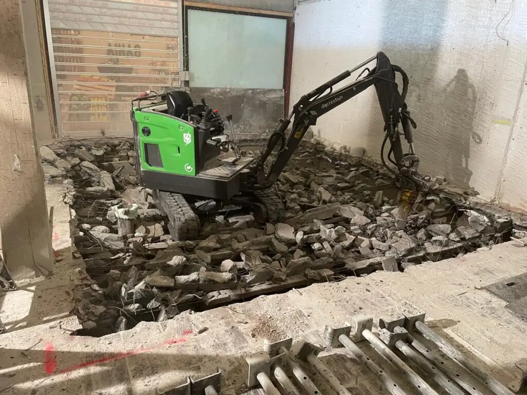 Betonvloer slopen met behulp van een minikraan