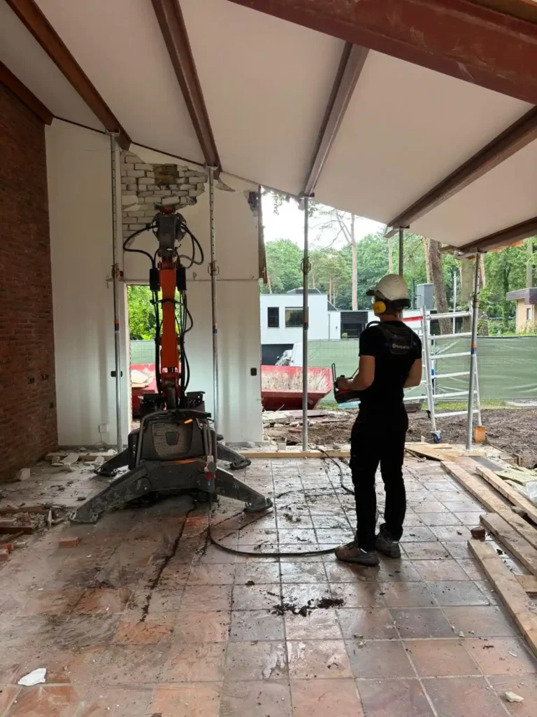 Sloopwerker is bezig met het slopen van een wand met behulp van een slooprobot